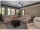 Large living room featuring leather sofas, multiple windows, and a dark wood coffee table at 100 Trotters Ridge, Fayetteville, GA 30215