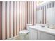 Compact bathroom featuring striped wallpaper, white fixtures, and a clean, functional design at 3244 Hampton Se Ct, Smyrna, GA 30082