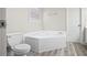 Bathroom featuring large corner bathtub, toilet, gray walls, and wood-look flooring at 1027 Regency Dr, Acworth, GA 30102