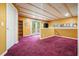 Spacious finished basement with purple carpet, wood ceiling, bookcase, and access to the backyard at 2004 Spicers Ln, Woodstock, GA 30189