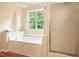 Bright bathroom with a soaking tub next to a large window, adjacent to a glass-doored shower at 2004 Spicers Ln, Woodstock, GA 30189