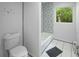 Bathroom with decorative accent wall above tub, tile floor, and window to the backyard at 2575 Flagstone Se Dr, Atlanta, GA 30316