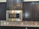 A modern stainless steel microwave is mounted above the granite countertop with stylish backsplash at 2948 Goldfinch Cir, Marietta, GA 30066