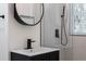 Modern bathroom with round mirror, shower with matte black fixtures, and vanity sink at 1582 Pine Cir, Austell, GA 30168