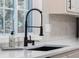 Close up of a modern kitchen sink with a black faucet and white countertops at 1582 Pine Cir, Austell, GA 30168