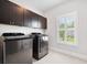 A laundry room featuring modern, front-loading washer and dryer sets and dark brown cabinets at 1596 Fearn Ne Cir, Brookhaven, GA 30319