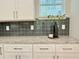 Kitchen detail featuring granite countertops, sleek gray backsplash, and white cabinetry at 2587 Ocean Walk Nw Dr, Atlanta, GA 30318