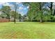 Lush backyard with mature trees, outbuilding, and brick house at 3799 Sweetbriar Cir, Lithia Springs, GA 30122