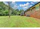 Large grassy backyard with mature trees, adjacent to the brick house and sunroom at 3799 Sweetbriar Cir, Lithia Springs, GA 30122