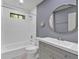 Well-lit bathroom featuring a tub with shower and modern gray vanity with a round mirror at 510 Watergate Ct, Roswell, GA 30076