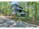 Two-story home with dark siding, white trim, and a charming balcony nestled amongst mature trees at 510 Watergate Ct, Roswell, GA 30076