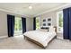Bright bedroom with neutral walls, plush carpet, large windows with dark blue curtains, and a ceiling fan at 3338 Breton Ne Cir, Brookhaven, GA 30319