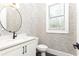 Stylish powder room featuring patterned wallpaper, white vanity, round mirror and black hardware at 3338 Breton Ne Cir, Brookhaven, GA 30319