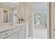 Bright bathroom featuring a white vanity with neutral walls, a large mirror, and doorway leading to a carpeted bonus room at 4915 Lazy Creek Ct, Cumming, GA 30028