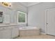 Relaxing bathroom with a bathtub, tiled floor, vanity, and a window at 4915 Lazy Creek Ct, Cumming, GA 30028