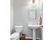 Cozy powder room with pedestal sink, toilet, decorative mirror, and hardwood floors at 4915 Lazy Creek Ct, Cumming, GA 30028