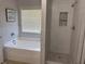 Bright bathroom featuring a soaking tub and a beautifully tiled shower with a built-in niche at 1221 St James Pl, Loganville, GA 30052