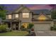 Charming two-story home featuring manicured lawn, neutral siding, a dark roof, and an attached two-car garage at dusk at 230 Haleys Ct, Woodstock, GA 30188