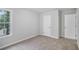 Neutral carpeted bedroom features a bright window and two white doors to closet and hallway at 2681 Lakeside Sw Dr, Conyers, GA 30094