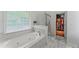 Bright bathroom featuring a soaking tub, glass shower, and walk-in closet for easy access at 9048 River Bend Ct, Villa Rica, GA 30180