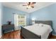 This bedroom features light blue walls, hardwood floors, a ceiling fan, and lots of natural light at 9048 River Bend Ct, Villa Rica, GA 30180
