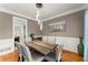 Dining room with modern chandelier, wood table, grey chairs, and wainscoting at 9048 River Bend Ct, Villa Rica, GA 30180