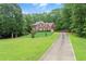 Brick home featuring a long driveway and spacious front lawn surrounded by mature trees at 9048 River Bend Ct, Villa Rica, GA 30180