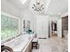 Spacious bathroom with a chandelier, large window, and a soaking tub, next to a big decorative mirror at 162 Daltree Ct, Marietta, GA 30068