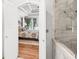 Arched doorway view to bedroom, showcasing marble bath and shower with seamless glass door and hardwood floors at 162 Daltree Ct, Marietta, GA 30068