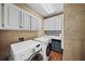 Bright laundry room features modern appliances, white cabinets, stylish countertops and backsplash, and durable wood-look flooring at 162 Daltree Ct, Marietta, GA 30068