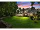 Stunning backyard view highlighting stone retaining wall, lawn, and sunroom during the evening at 2595 Winthrope Way, Lawrenceville, GA 30044