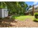 Spacious backyard with stone retaining wall, lush green lawn, storage shed, and screened sunroom at 2595 Winthrope Way, Lawrenceville, GA 30044