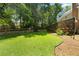 Lush backyard featuring a stone retaining wall, verdant lawn, and a sunroom addition to the home at 2595 Winthrope Way, Lawrenceville, GA 30044