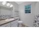 Bright bathroom featuring a vanity sink, toilet, and shower/tub combination with white and black floral curtain at 402 Wood Chase Ln, Canton, GA 30114
