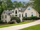 Elegant home featuring a neutral stucco exterior, arched windows, lush landscaping, and a private driveway at 5940 Plantation Dr, Roswell, GA 30075