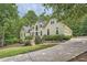 An elegant home nestled among lush trees, showcasing a multi-car garage and circular driveway at 5940 Plantation Dr, Roswell, GA 30075