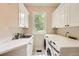Clean and bright laundry room with modern washer and dryer and white cabinets at 5940 Plantation Dr, Roswell, GA 30075