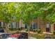 Street-level view of townhomes with stone accents and blue shutters, shaded by mature trees at 1851 Grove Way, Hampton, GA 30228