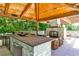 A deluxe outdoor kitchen featuring stone counter, gas grill, wood-burning fireplace and wooden covering at 4309 Sentinel Post Nw Rd, Atlanta, GA 30327