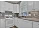 This kitchen features white cabinets, stainless steel appliances, and a gray tile backsplash at 530 Chicapoo Dr, Marietta, GA 30066
