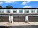 Modern townhome garages with gray doors, white siding, and black trim under a clear sky at 2406 Lakeshore Ln, Atlanta, GA 30316