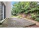 Concrete back patio surrounded by lush landscaping and stone retaining wall at 1684 Tailmore Ln, Lawrenceville, GA 30043