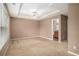 Spacious carpeted bedroom with a tray ceiling, ceiling fan and a door leading to the en-suite bathroom at 1684 Tailmore Ln, Lawrenceville, GA 30043