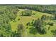 Expansive aerial view of a modern home situated on acres of green land with a backdrop of dense woodland at 1971 Centennial Rd, Rutledge, GA 30663
