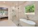 Spa-like bathroom with a glass-enclosed shower, soaking tub, marble walls, and view to the connected bedroom at 2625 Beverly Ln, Snellville, GA 30078