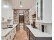 Modern kitchen featuring white cabinets, quartz countertops, brick accent wall, and a walk-in pantry with a wine rack at 2625 Beverly Ln, Snellville, GA 30078