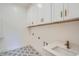 Practical laundry room with upper cabinets, tile flooring, a utility sink, and modern fixtures at 2625 Beverly Ln, Snellville, GA 30078