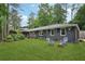 Well-manicured front yard with mature trees, green grass and chairs around fire pit at 2762 Whispering Pines Dr, Decatur, GA 30033