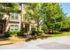 Brick townhouse with covered front door entrance, landscaping, and mature trees at 1420 Baygreen Rd, Suwanee, GA 30024