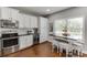 This kitchen features white cabinets, stainless appliances, and a dining area with stools at 440 S Alexander St, Buford, GA 30518